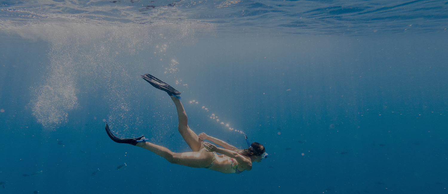 woman diving further into water in snorkeling gear