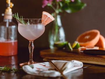 table with elegantly decorated cocktail with a grapefruit and rosemary garnish