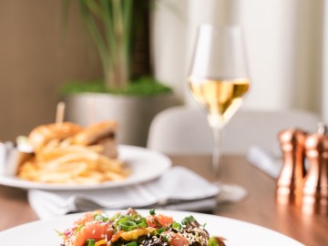 Ahi tuna salad with another dish out of focus in the background with a glass of white wine