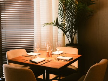 Intimate setting for a private dining table with chairs and plant in background