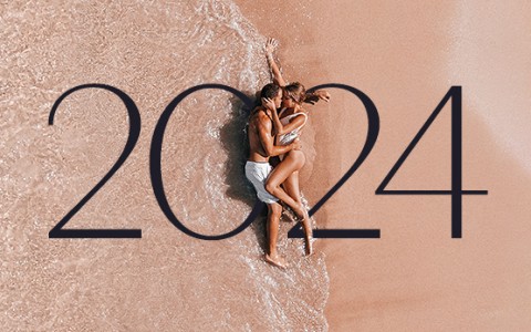 a couple laying on the sand while the ocean tide comes up and the numbers 2024 are displayed in the middle