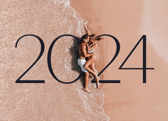 a couple laying on the sand while the ocean tide comes up and the numbers 2024 are displayed in the middle 