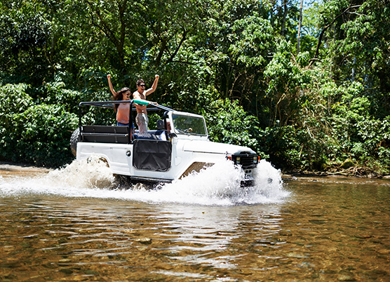 couple driving a white jeep through deep water in the foset