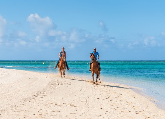 2 people horseback riding on the beach