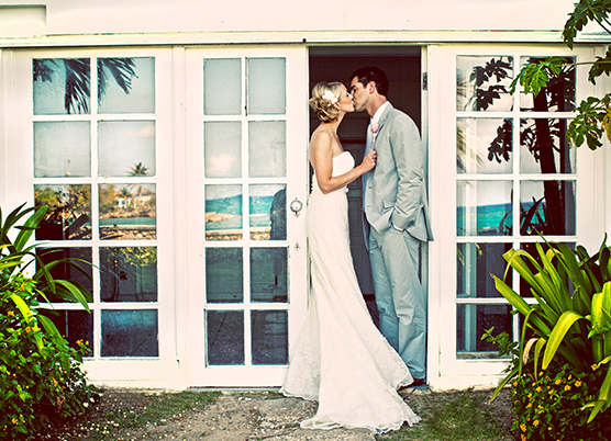 a bride and groom kiss standing in a door entrance