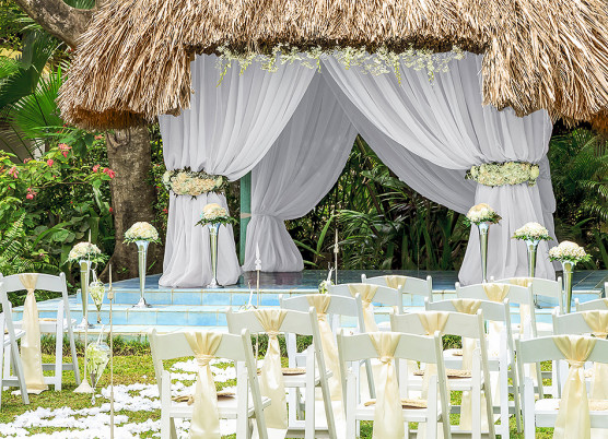 wedding ceremony set up at a tiki hut with white drapes hanging to the side