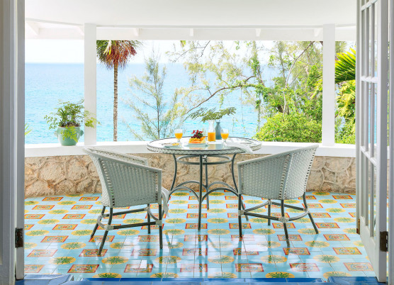 hibiscus cottage balcony with white whicker seating and colorful tile floors