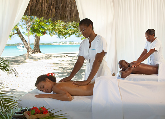 a couple getting a couples massages at an outdoor spa covered with white curtains