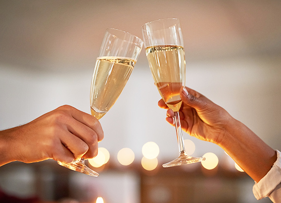 close up of a couple holding out glasses of champagne for a toast