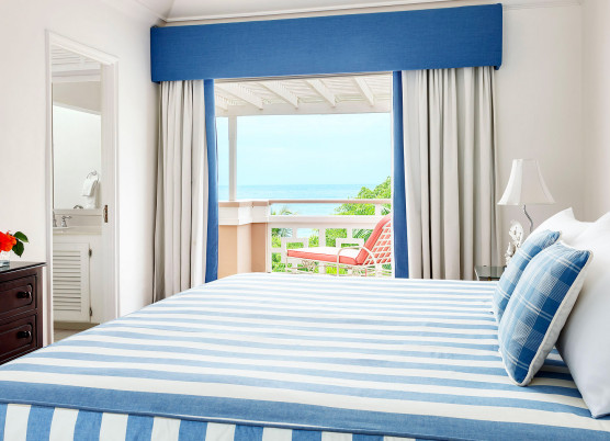 penthouse suite with blue and white striped furniture with balcony window overlooking the ocean