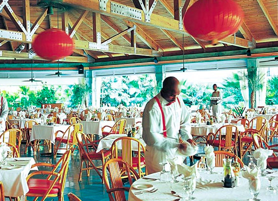 a waiter preparing table settings for dinner at a covered outdoor restaurant