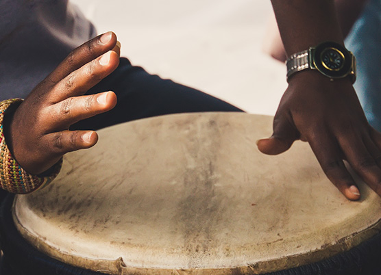 close up of a persons hands playing a wooden drum