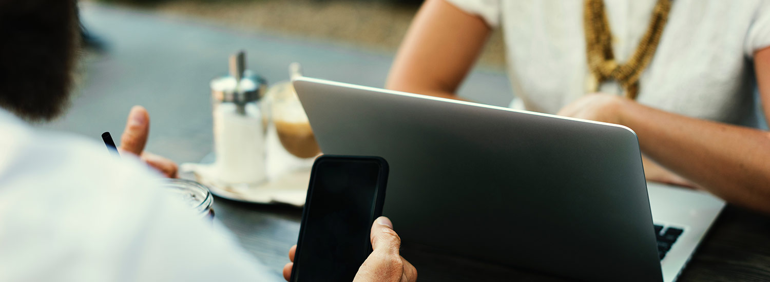 a man and woman working on their electronics at a coffee shop