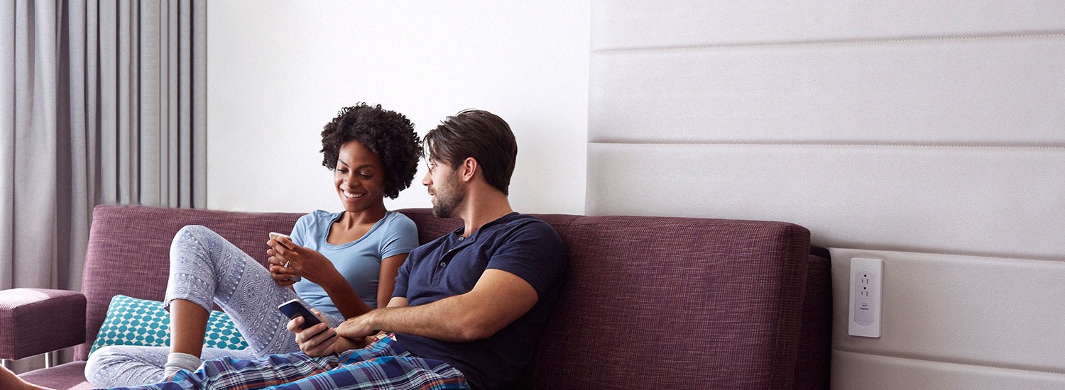a man and woman sit together on a purple couch in a nook