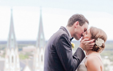 a bride and groom kissing on the balcony