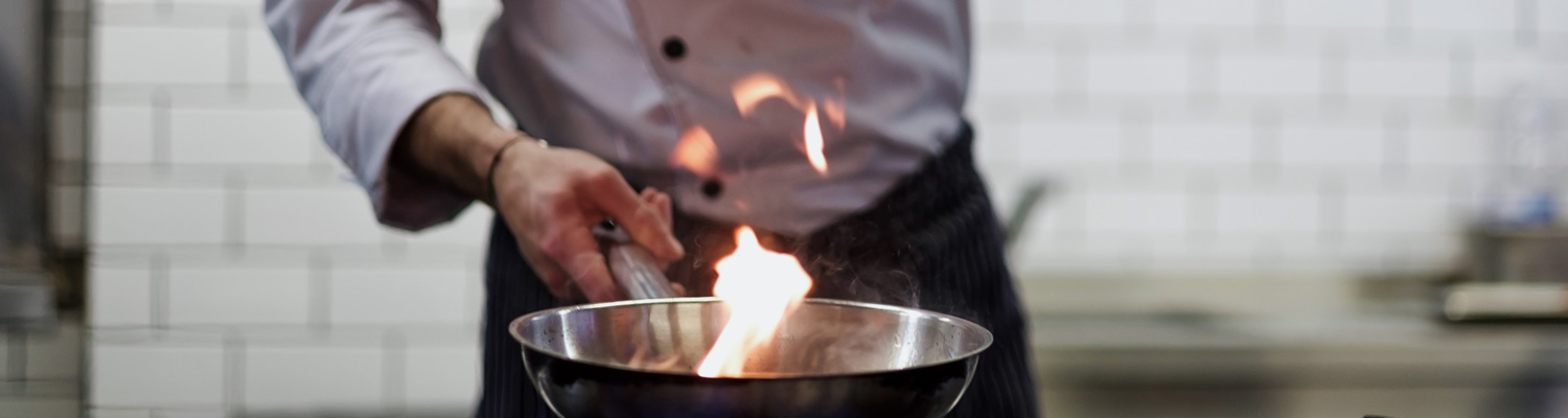 Close up of chef holding pan with fire