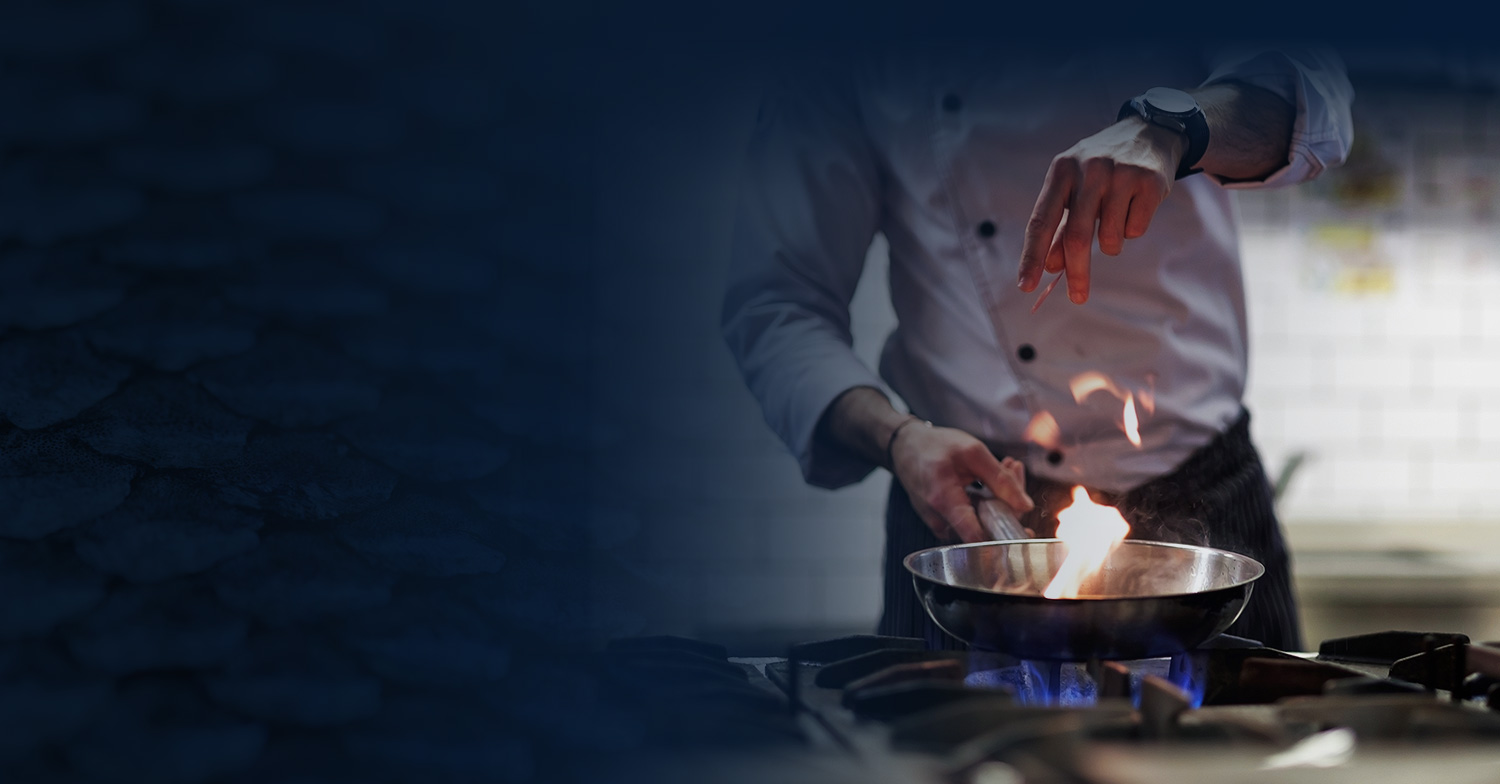 Close up of chef seasoning food in pan with fire