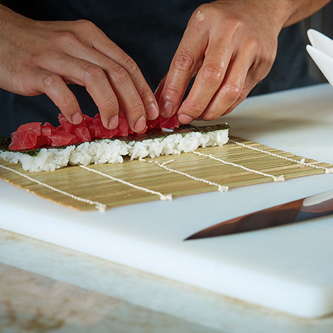 Close up of hands rolling sushi