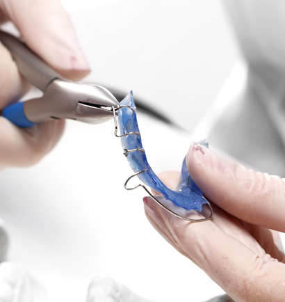 Close up of doctor twisting wire on retainer with pliers
