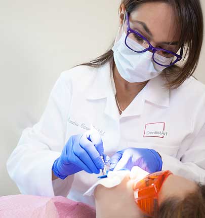 Doctor with mask working on young girl&#39;s teeth