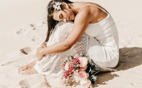 bride curled in a ball on the beach