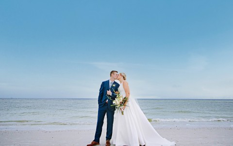 bride and groom kissing on the beach