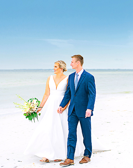 bride and groom walking in the beach while they are looking to the view 