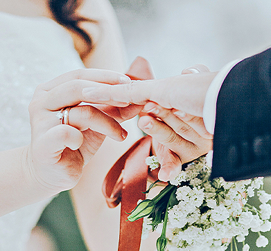 close up view of the hands of bride and groom putting their marriage ring on 