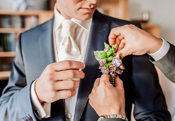 body of a groom putting a small roses in his blazer 