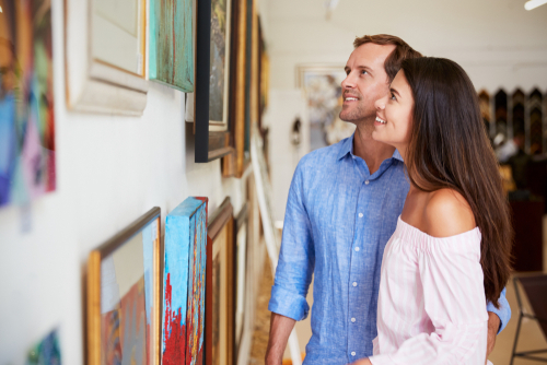 couple looking at paintings in art gallery
