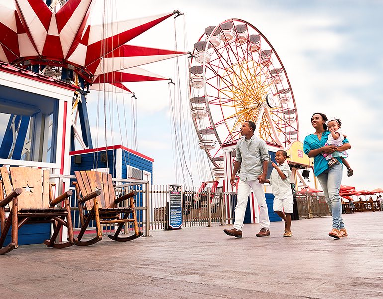 A family walks on the pier and looking at all the different rides