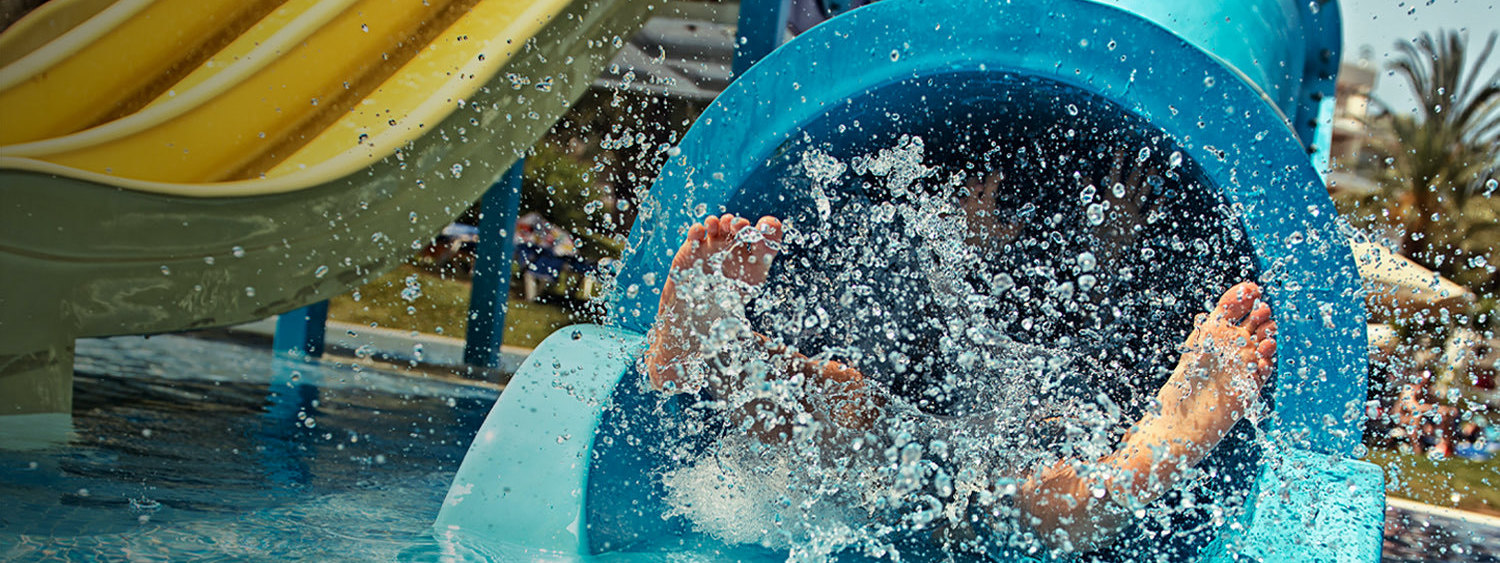 little kid coming down a waterslide at a waterpark