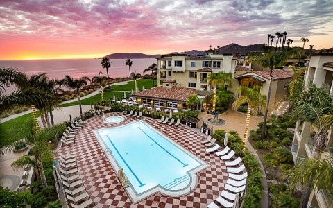 aerial view of resort pool as the sun is setting a pink color 