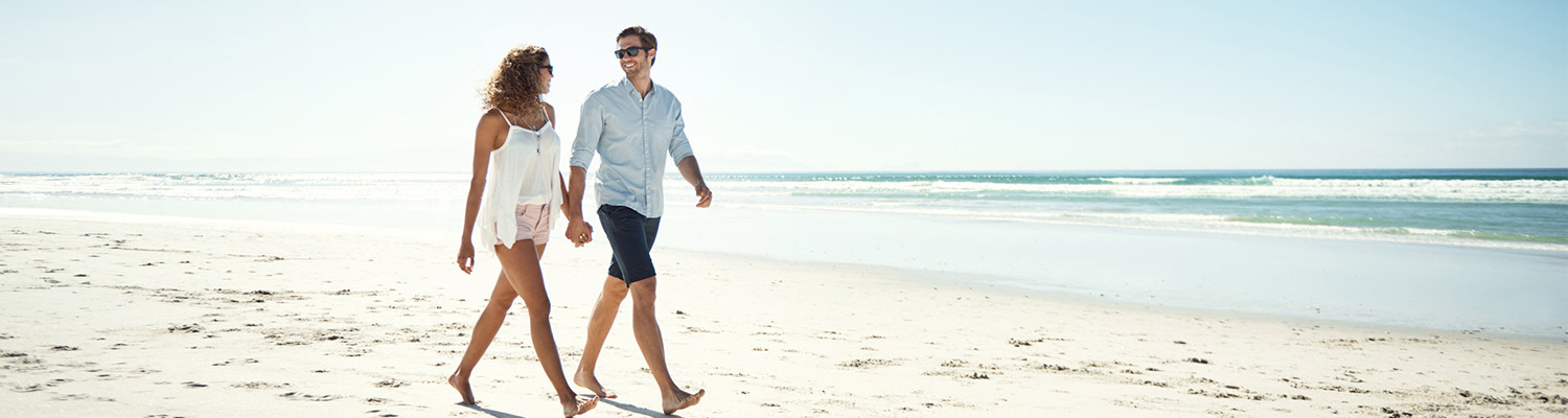 couple walking barefoot on the beach sand