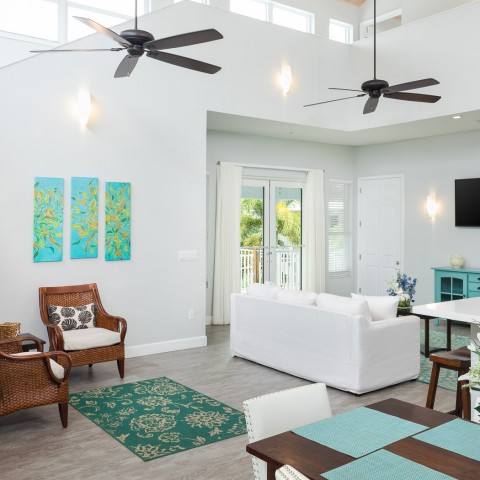 living room with white couches and two ceiling fans