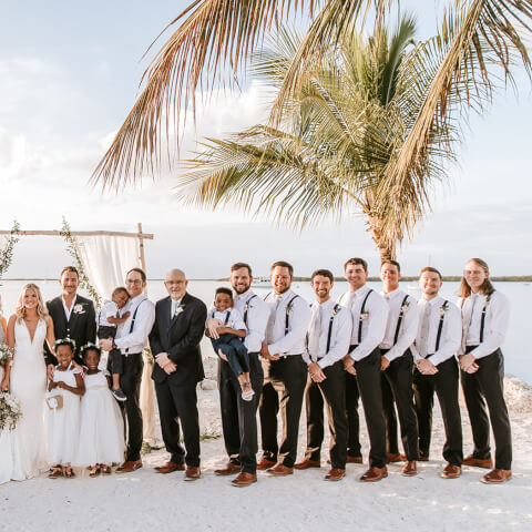 large bridal party posing in front of ocean