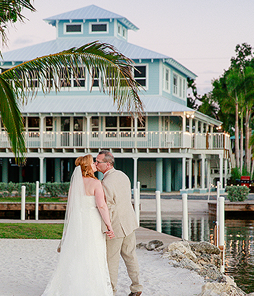 bride and groom kissing in front of a blue building
