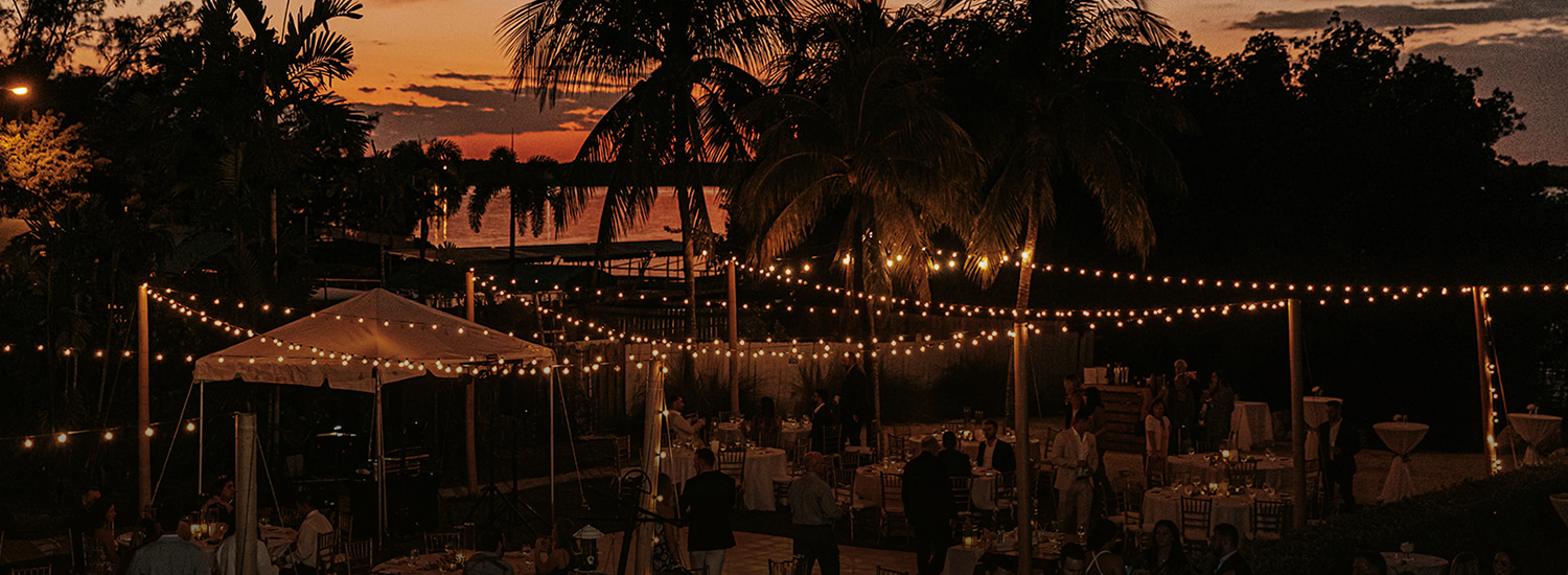 string lights hanging above a wedding reception at night