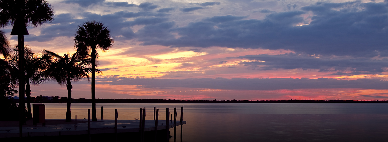 view of the ocean water at sunset with purple and pink skies