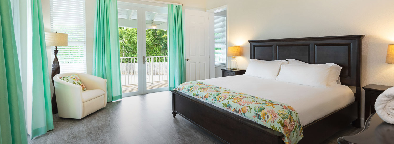 large bed with tropical throw blanket and teal curtain