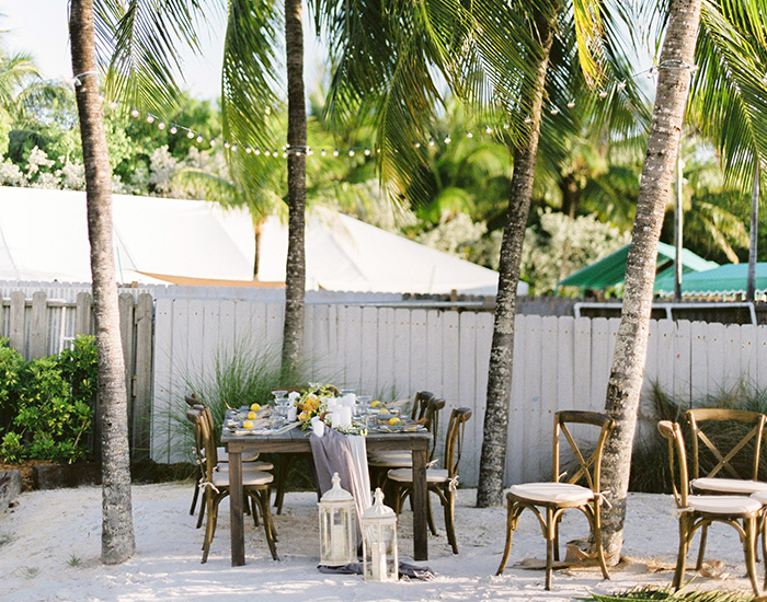 long rectangular wooden table inbetween trees for a venue