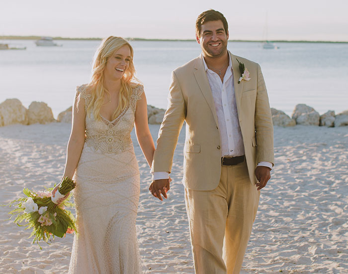 bride and groom walking on the beachy sand at sunset