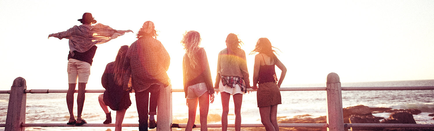 group of friends hanging by the beach at sunset