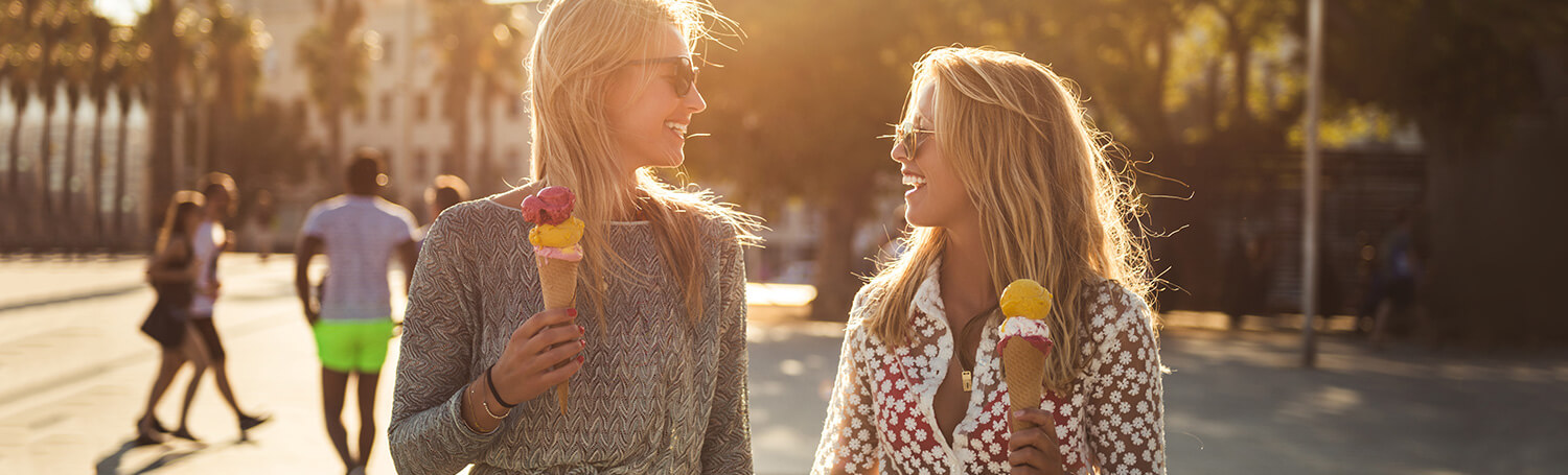 Two young women walking down the street eating ice cream cones