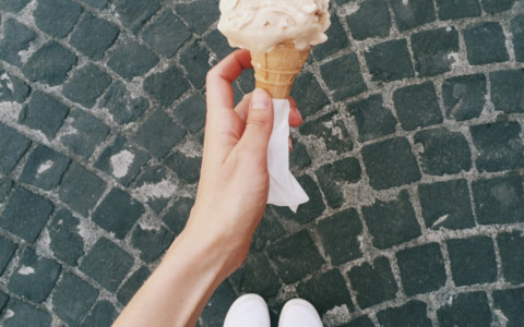 girl wearing white sneakers holding an ice cream cone