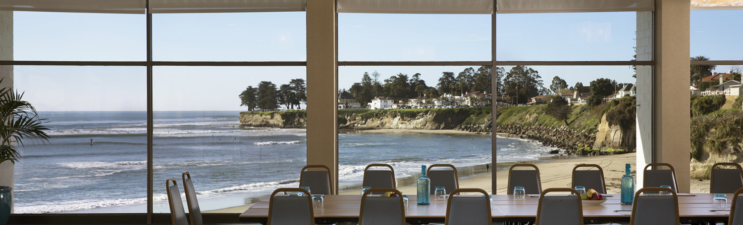 event space with floor to ceiling windows overlooking the beach set for a board meeting