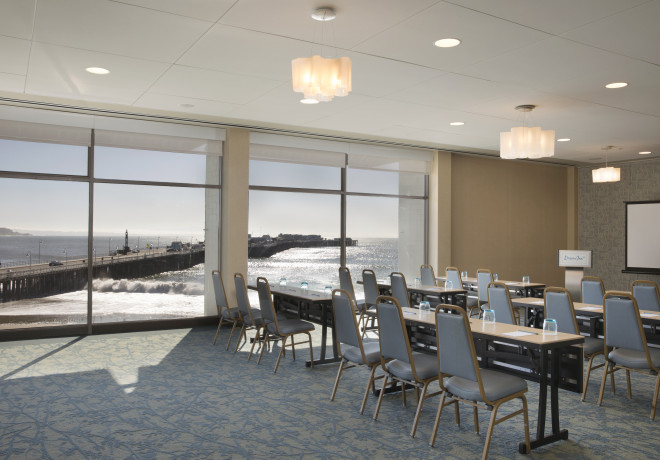 beach-view-room - event space with floor to ceiling windows overlooking the beach set for a board meeting