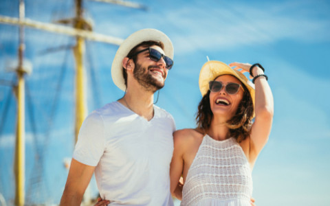 couple walking in front of a large sail boat laughing 