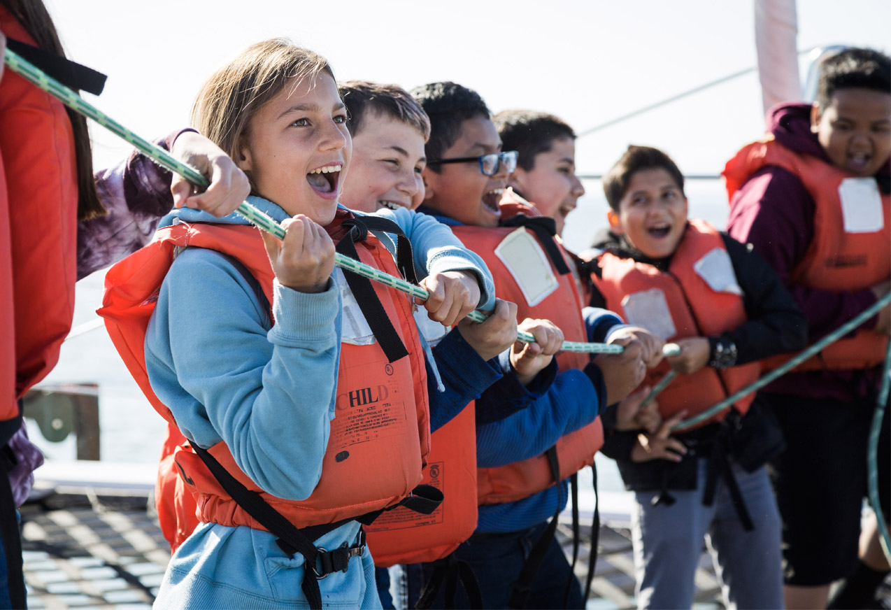 kids wearing life jackets holding a rope