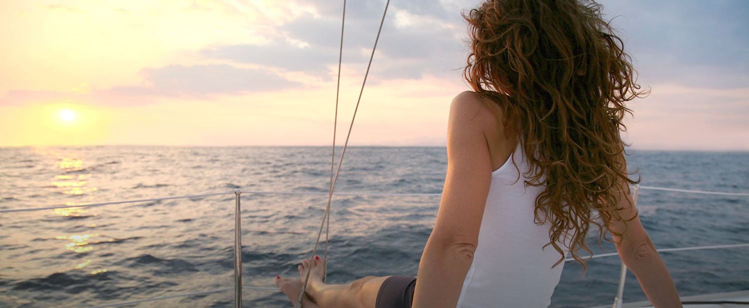 woman sitting on front of boat gazing into the sunset